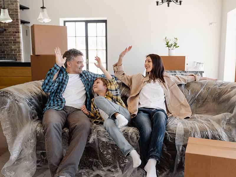 Family sitting on couch with moving boxes around them