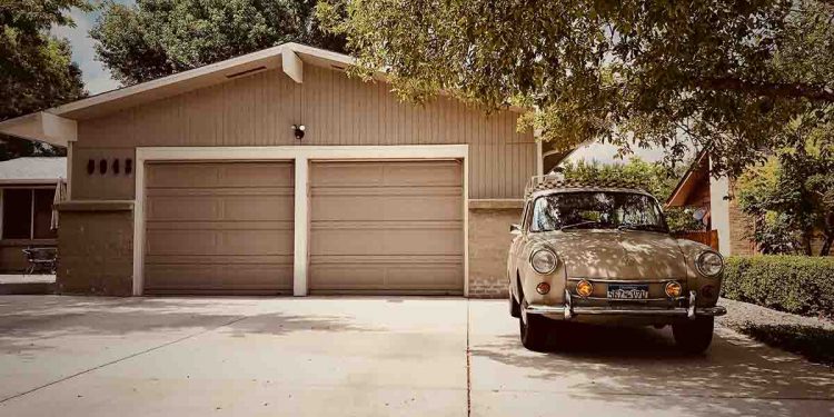tan garage and car parked next to tree