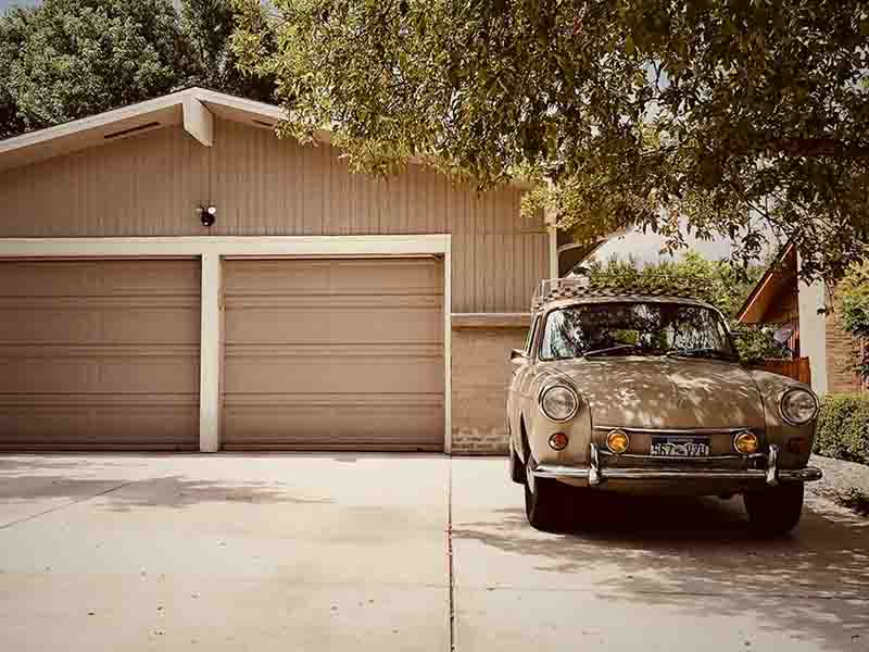 tan garage and car parked next to tree