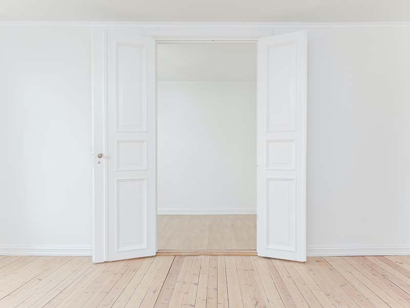 White room with wooden floor and open doors