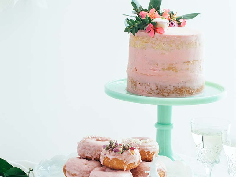 Pink cake and donuts on plates and stands