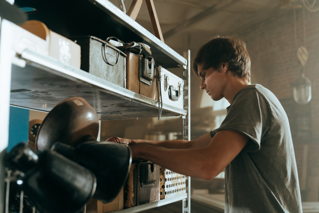 Man placing items in a storage box on a shelf.