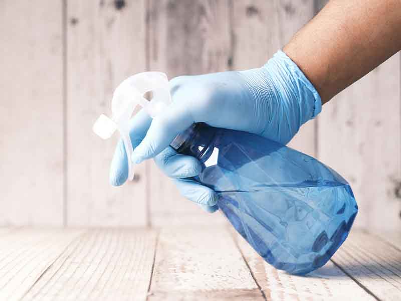 Person with gloves and spray bottle cleaning.