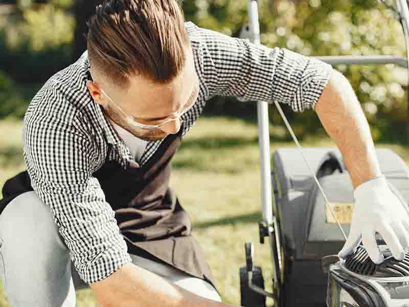 Man inspecting lawn mower