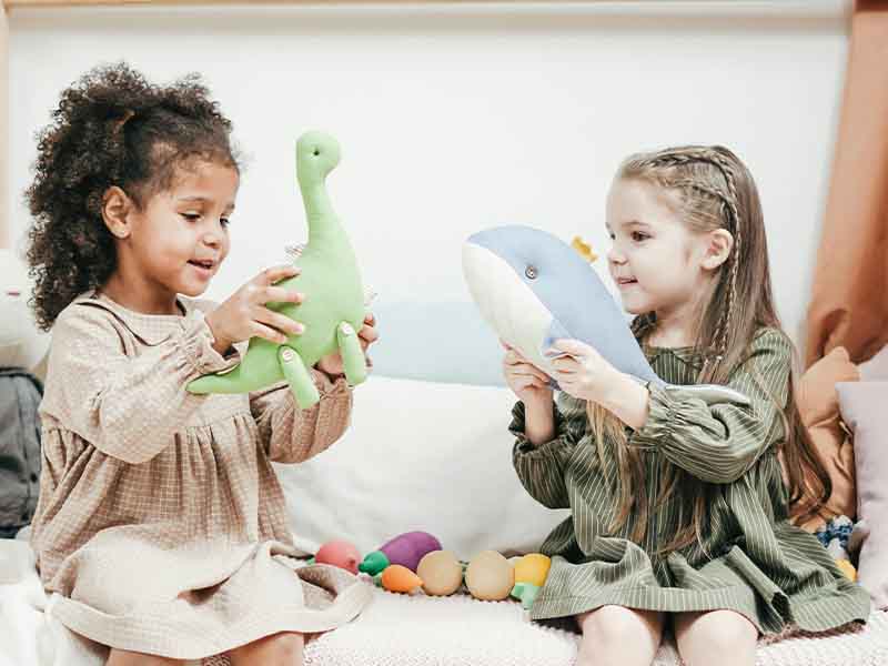 Two girls playing with toys in a playroom