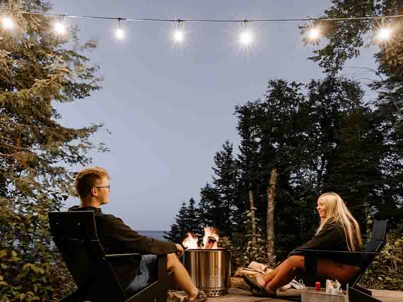 Couple sitting on patio with Edison bulb lights and firepit