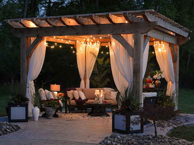 Pergola with drapes, lights, and furniture 