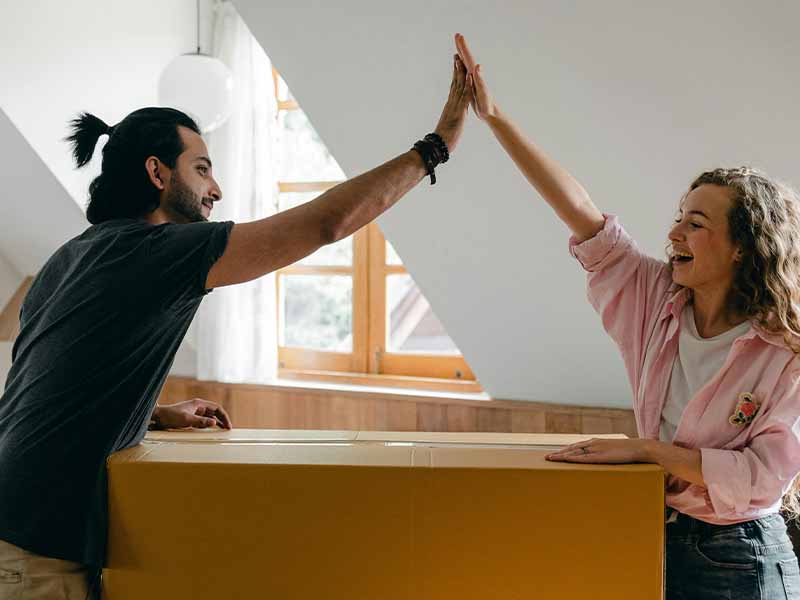 Couple high fiving over cardboard box