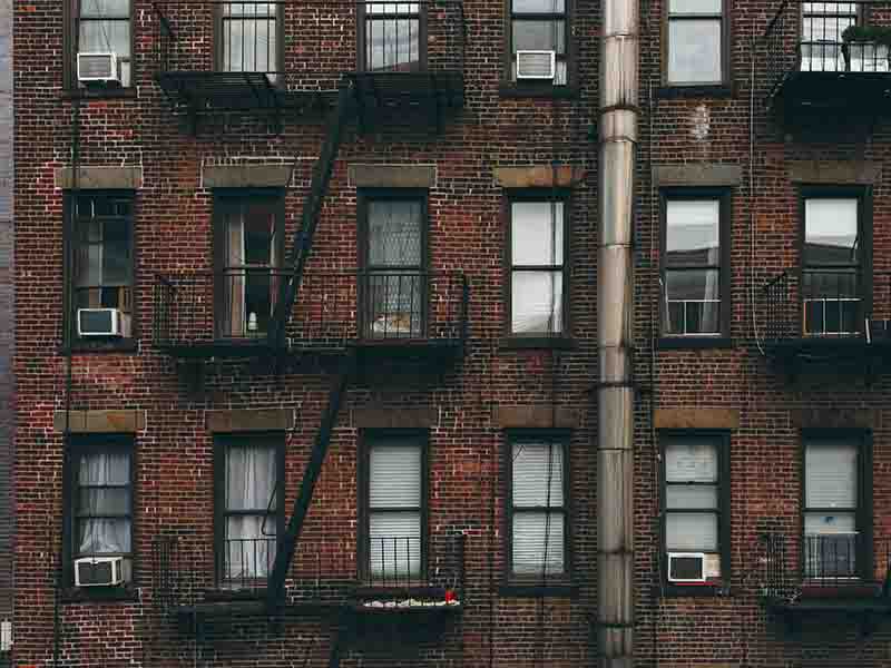 Shot of brick apartment building with lots of window and fire escape