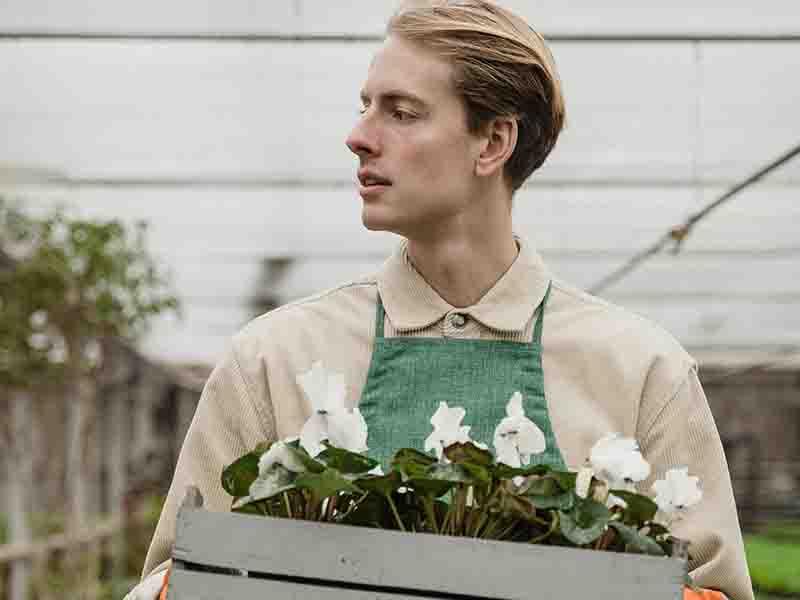 Man with apron holding crate of flowers