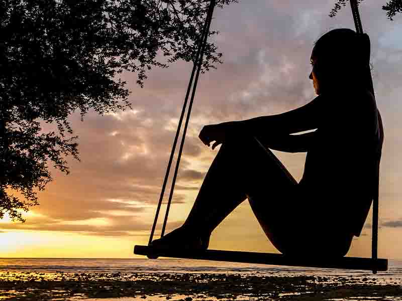 Silhouette of woman on swing during golden hour