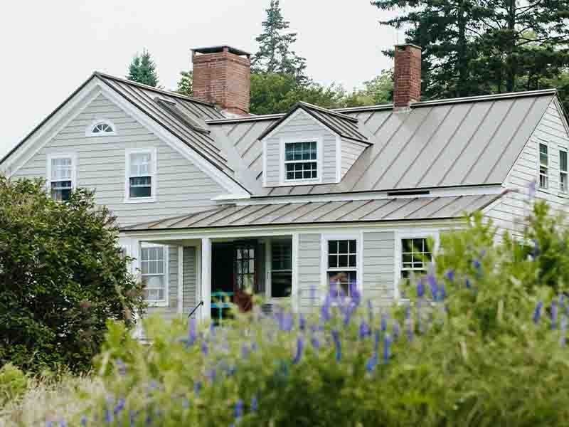 Gray home with purple flowers in garden
