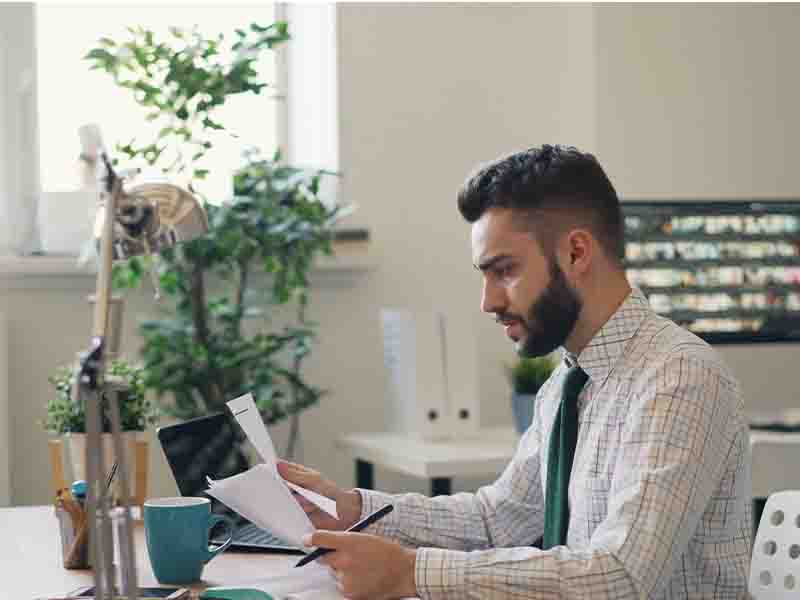 Man sitting at desk, looking at paperwork