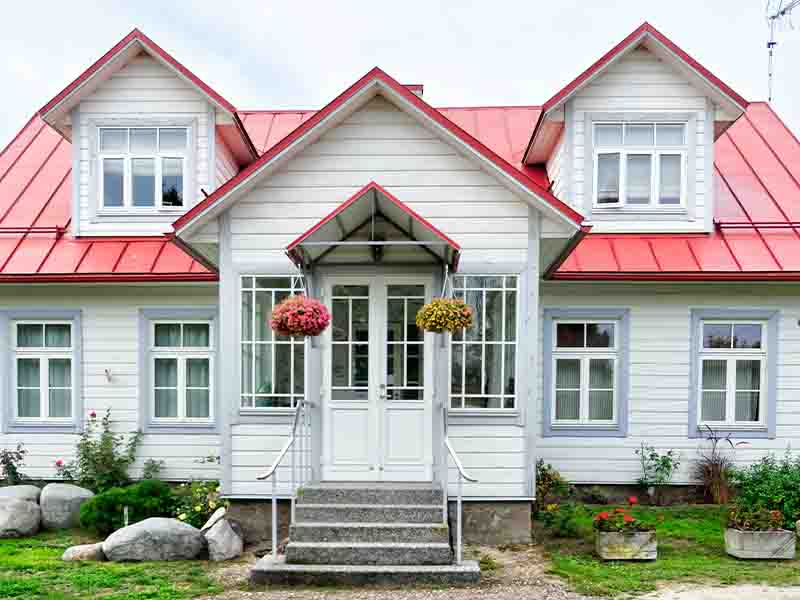 White and red cottage with flowers hanging on porch