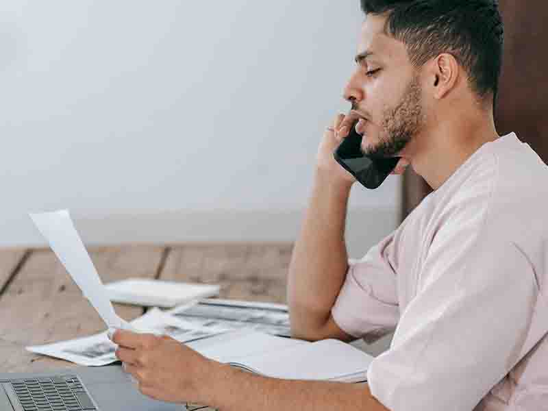 Man holding papers and talking on phone