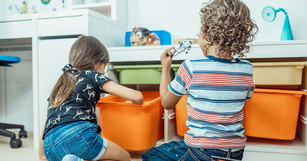 children playing next to toy storage bins