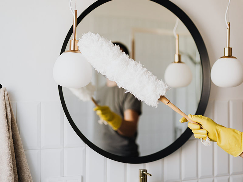 Person dusting a light fixture