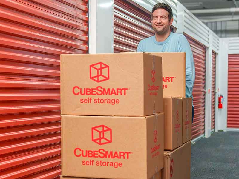 Man pushing moving boxes in storage unit