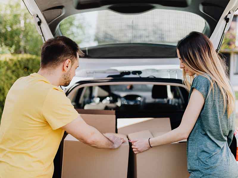People moving boxes out of trunk