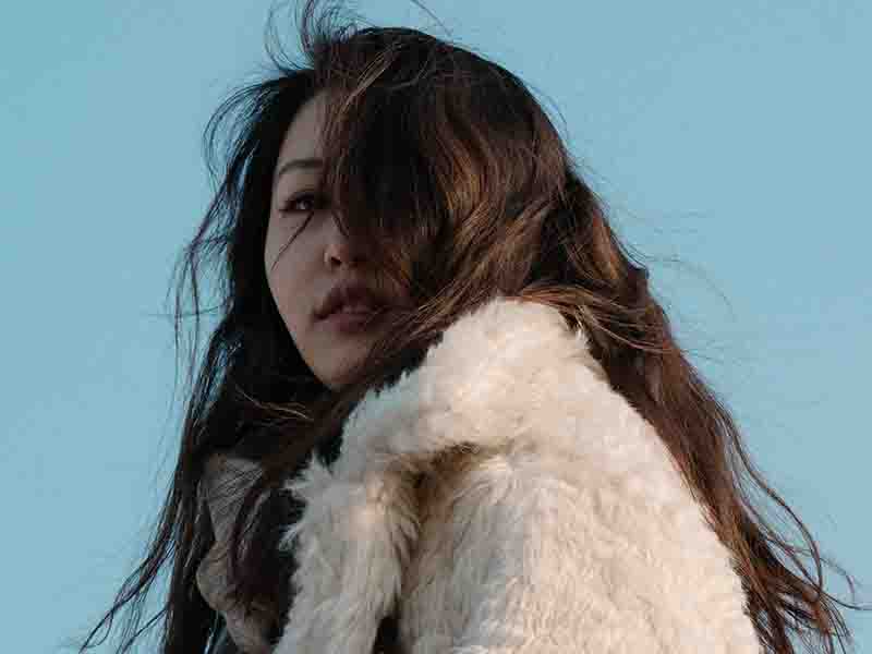 Woman wearing a faux fur jacket with blue sky in background