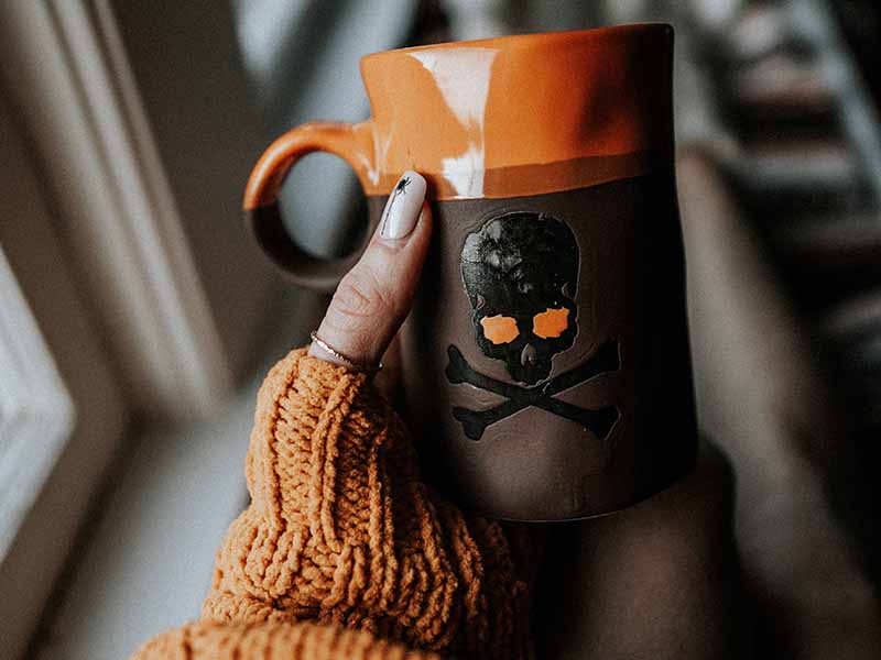 Woman's hand holding halloween inspired coffee mug