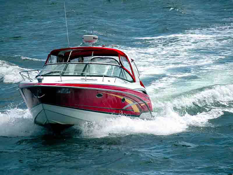 A small red and white motorized boat sailing in white crest on the Long Island Sound